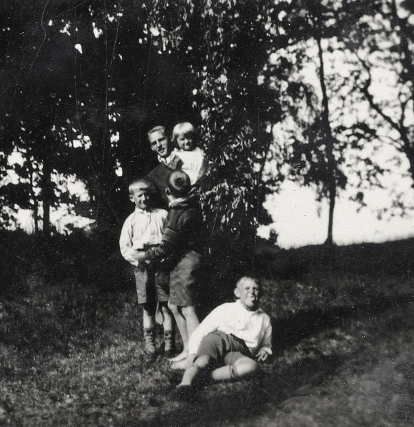 En ung man med några små barn i en ekbacke.