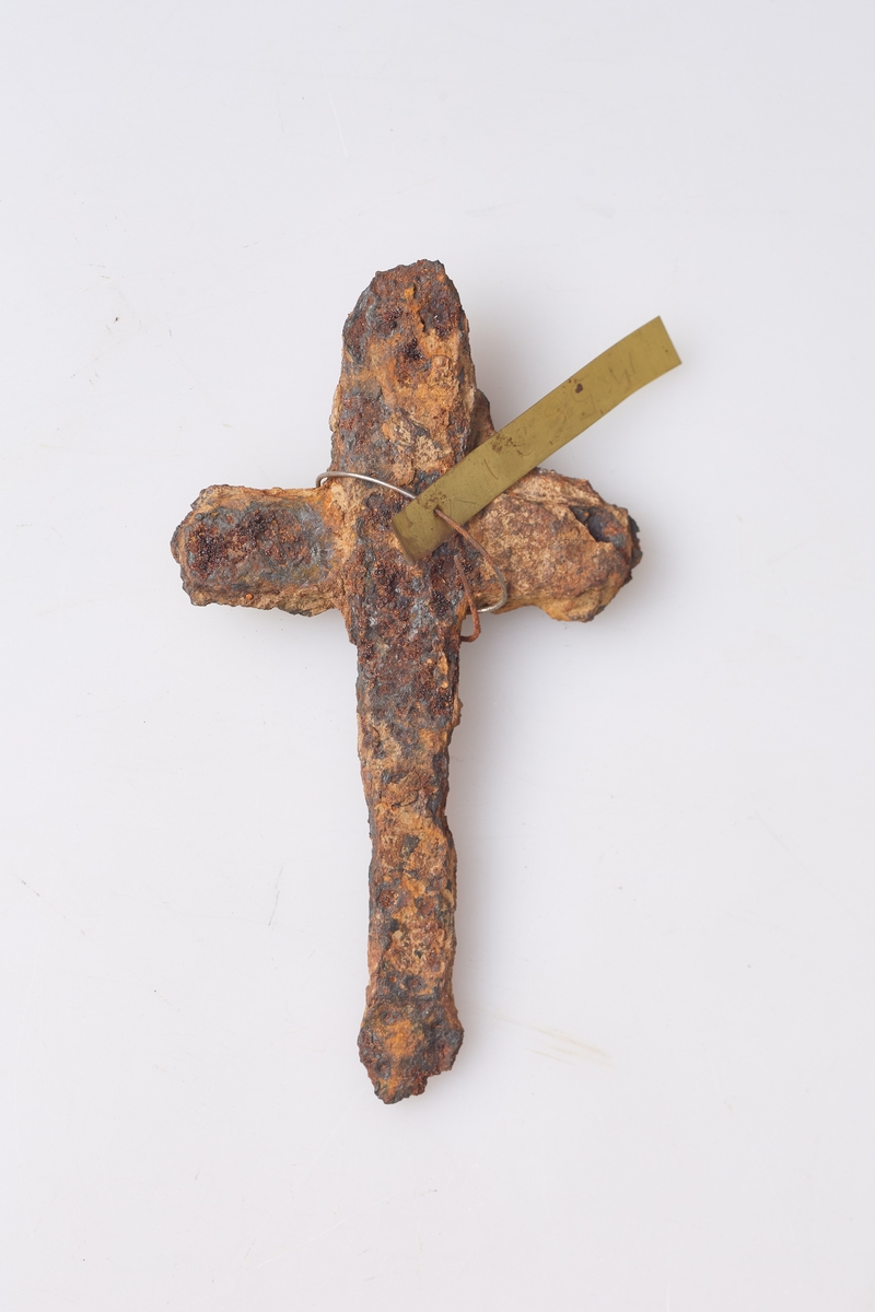 Forrustet kors eller beslag av jern, mest sannsynlig rester av et beslag. Heimesmidd, klumpete, funnet i hagen.