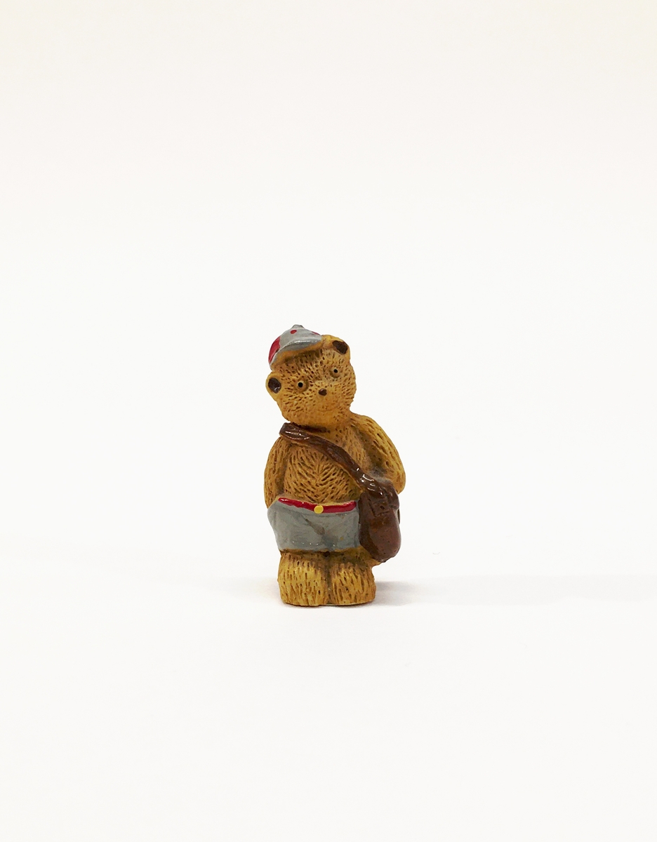 Figurin förställande en björn med axelremsväska.