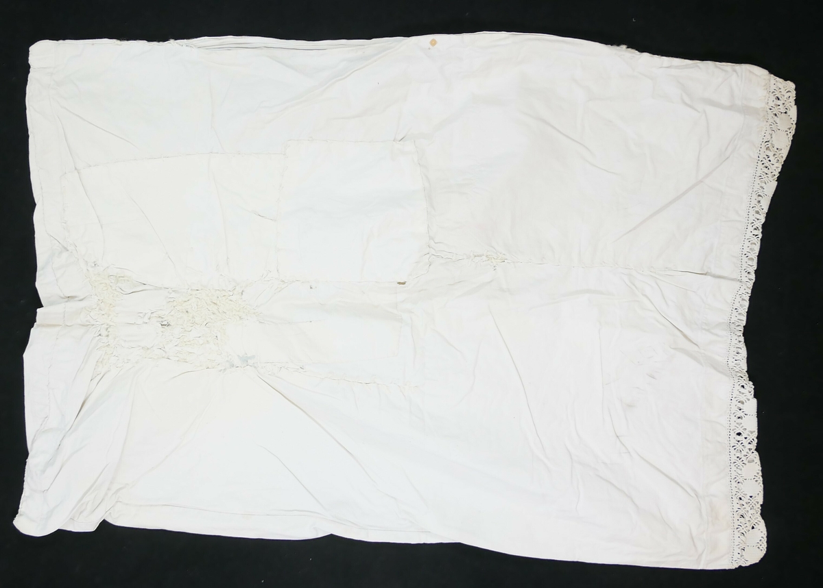 Rektangulært putevar i hvit tekstil med blondekant på den ene kortsiden. 