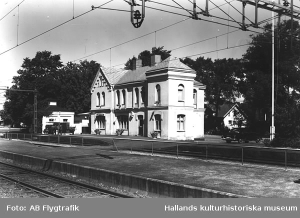 Exteriörbild av Tvååkers järnvägsstation som uppfördes vid Mellersta Hallands järnväg, invigd 1886. Stationen hade ursprungligen likadan utformning som den i Slöinge med bl a hög takspira, hörntorn och kraftigare fasaddekorer (arkitekt Adrian C Peterson ritade banans stationer).
