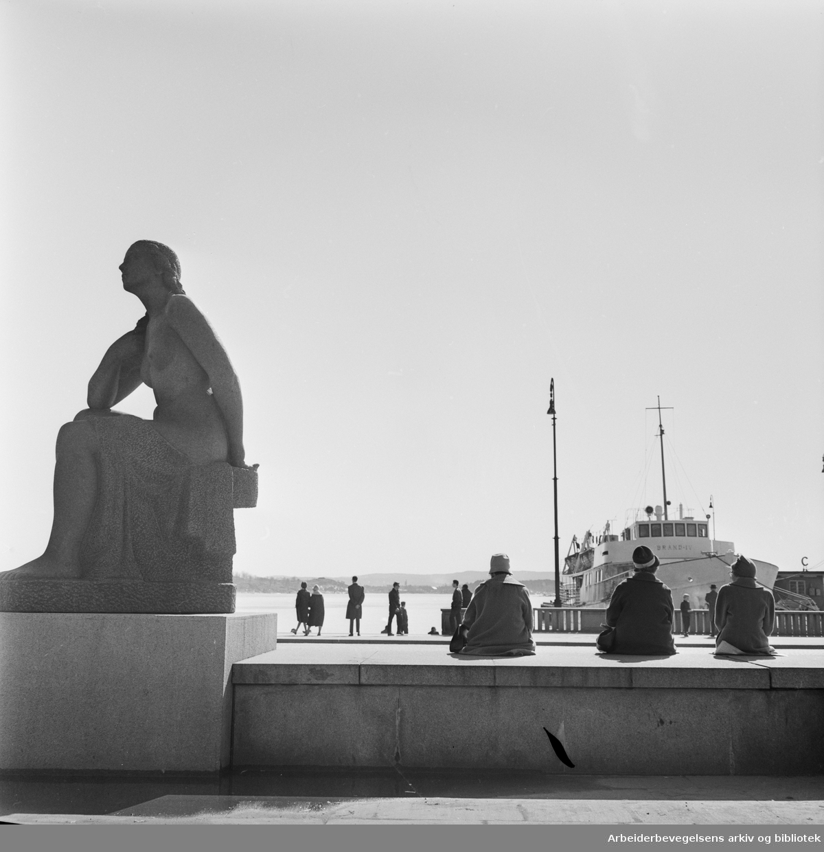 Vårstemning på Rådhusplassen i Oslo. M/S Brand VI ligger til kai. Til venstre: Emil Lies skulptur av sittende kvinne, reist 1954-58. 24. April 1962.