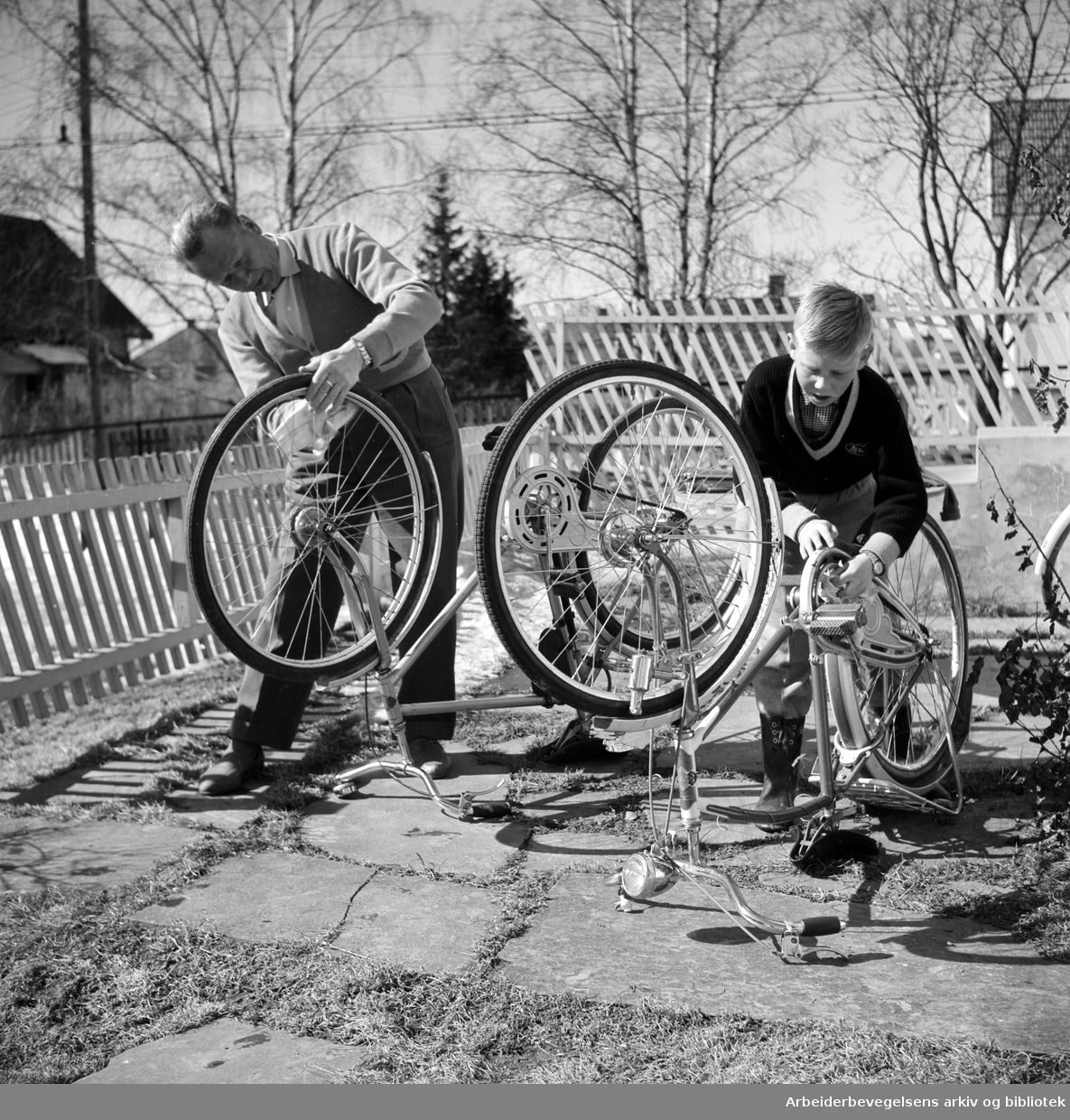 Far og sønn foretar vårens sykkelpuss. Villastrøk i Oslo-området. April 1958.