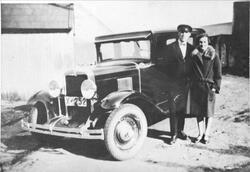 Kvinne og mann stående ved en drosje på en gårdsplass.