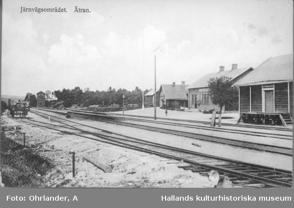 Vykort, "Järnvägsområdet. Ätran". Stationsområdet som det såg ut sedan Varberg-Ätrans Järnväg tillkommit 1911. För att få ansluta till den befintliga stationen i Ätran fick VÄJ, förutom bangårdens utvidgning, även betala nytt godsmagasin, ny stationsbyggnad (byggnaderna längst till höger) samt nytt vattentorn, den högsmala byggnaden till vänster vid spåren. Dock kunde de hyra in sig i det befintliga lokstallet men bekostade två nya stall samt vändskiva. Förlag: Ad. Andersson.