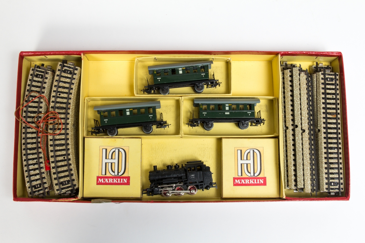 Modelltogsett fra Märklin i originalembalsje. Inneholder et damplokomotiv, tre personvogner og buede og rette skinner.