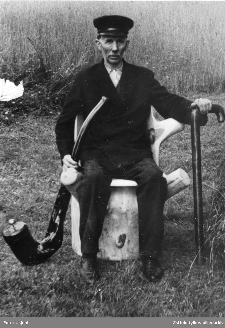 Portrett av Anton Bergby fra Varteig. Den stolen han sitter i og det han holder i hendene har han skåret ut. Han var gårdbruker og drev trelasthandel.