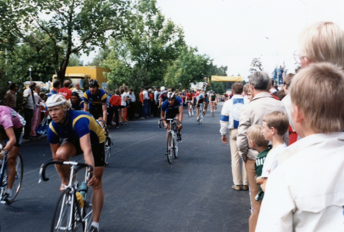 Cykellopp. Cyklister kör på en väg och publik står runt om. Troligtvis från cykeltävlingen Postgirot Open 1987.