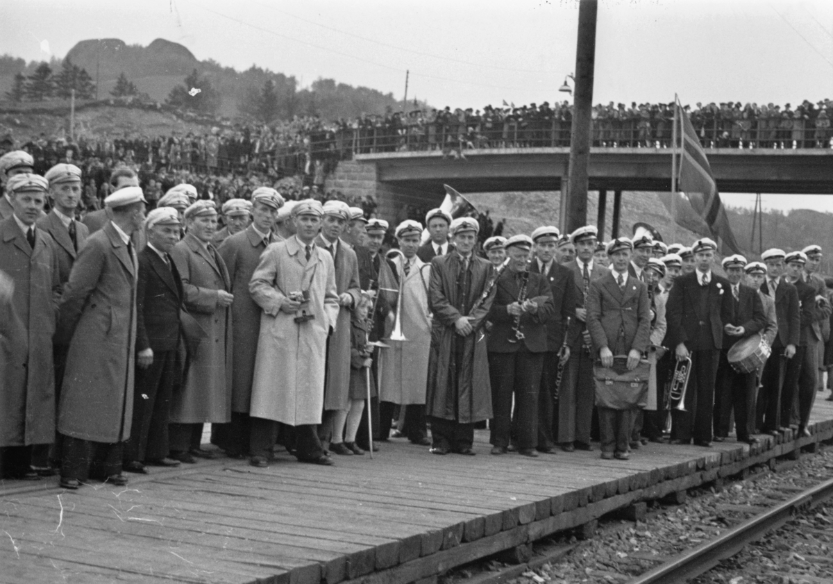 Jernbanestasjonen på Eie, 10. mai 1945. Musikkorps og sangere venter på toget med Grinifangene.