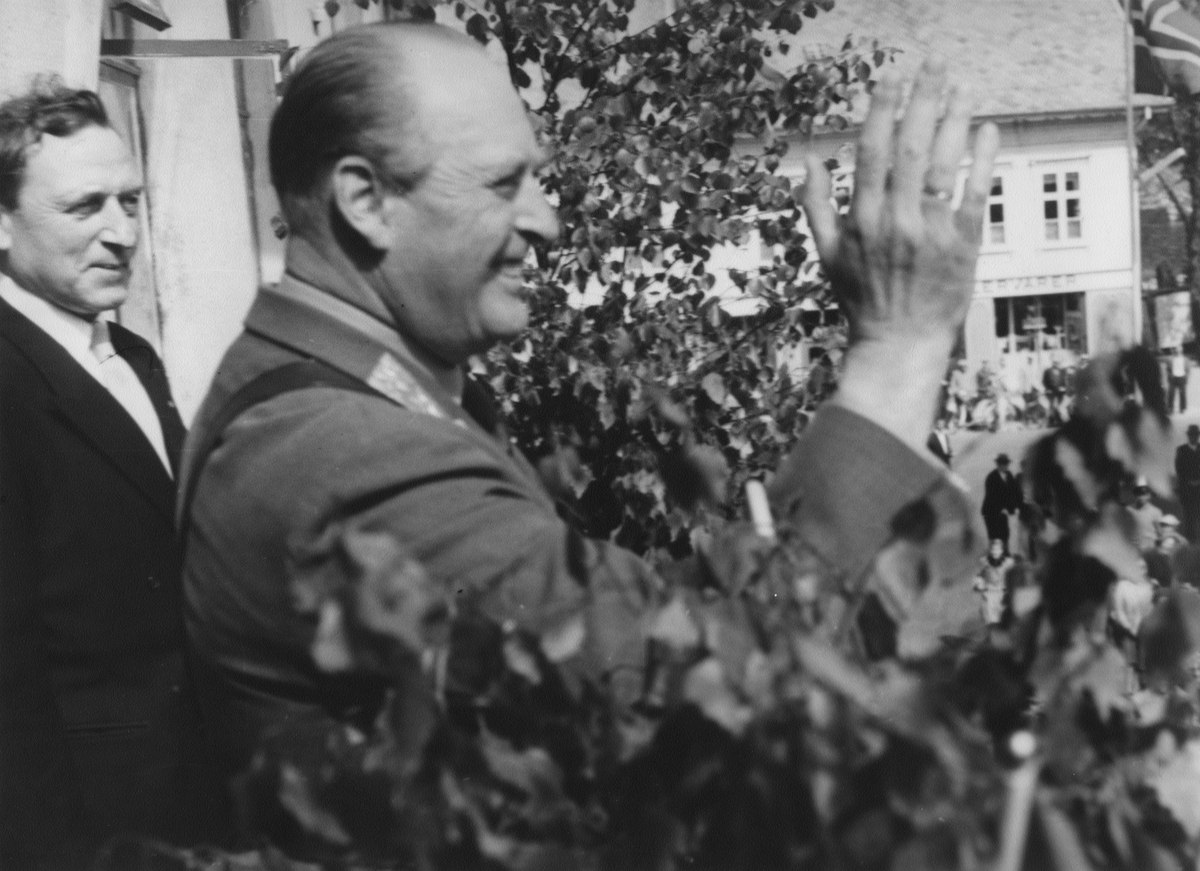 Kronprins Olav taler på Torget i anledning for elektrifiseringen av Sørlandsbanen, 1. juni 1956. Bak kronprinsen står ordfører Karl Jensen.