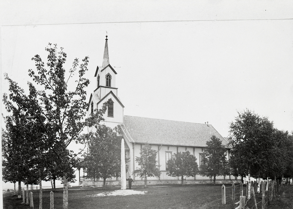 Bø kyrkje med bautaen reist i 1914 framfor