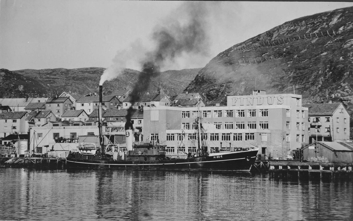 Findusfabrikken i Hammerfest med båten M-80-K som livgger ved kaia og Salenfjellet i bakgrunn.