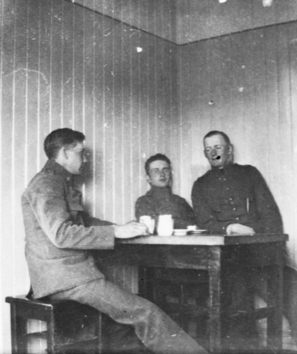 Tre militärer sitter vid ett fikabord, 1920-tal.