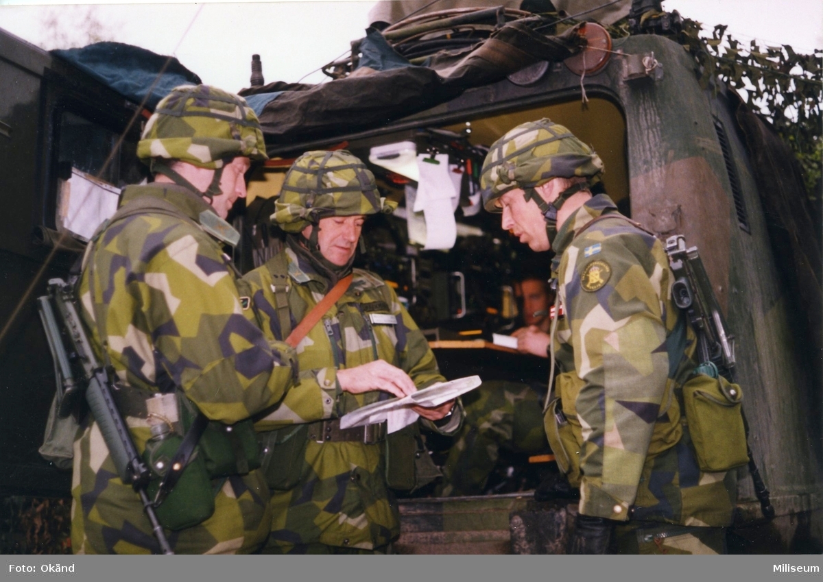 Brigadstab. Stabsarbete. Från vänster underrättelsechef major Per Sandgren, överste Thore Bäckman, brigadchef, I 12 och ?. I bakgrunden bandvagn 206.