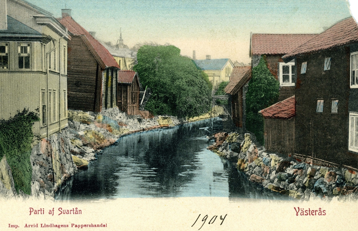 Det kolerade vykortet är taget av fotografen Elise Hirsch från Apotekarbron mot norr. På östra sidan av Svartån syns långt bort en tvätterska.