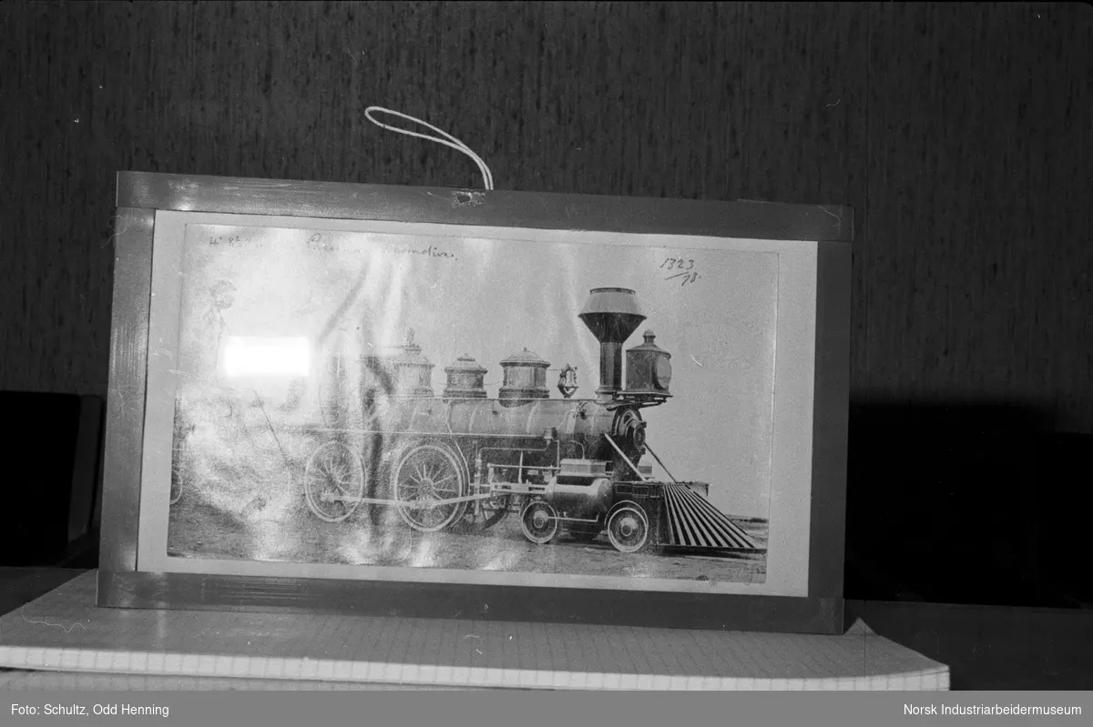 Fotografi av gammelt prærielokomotiv i ramme, som står på en notisblokk.