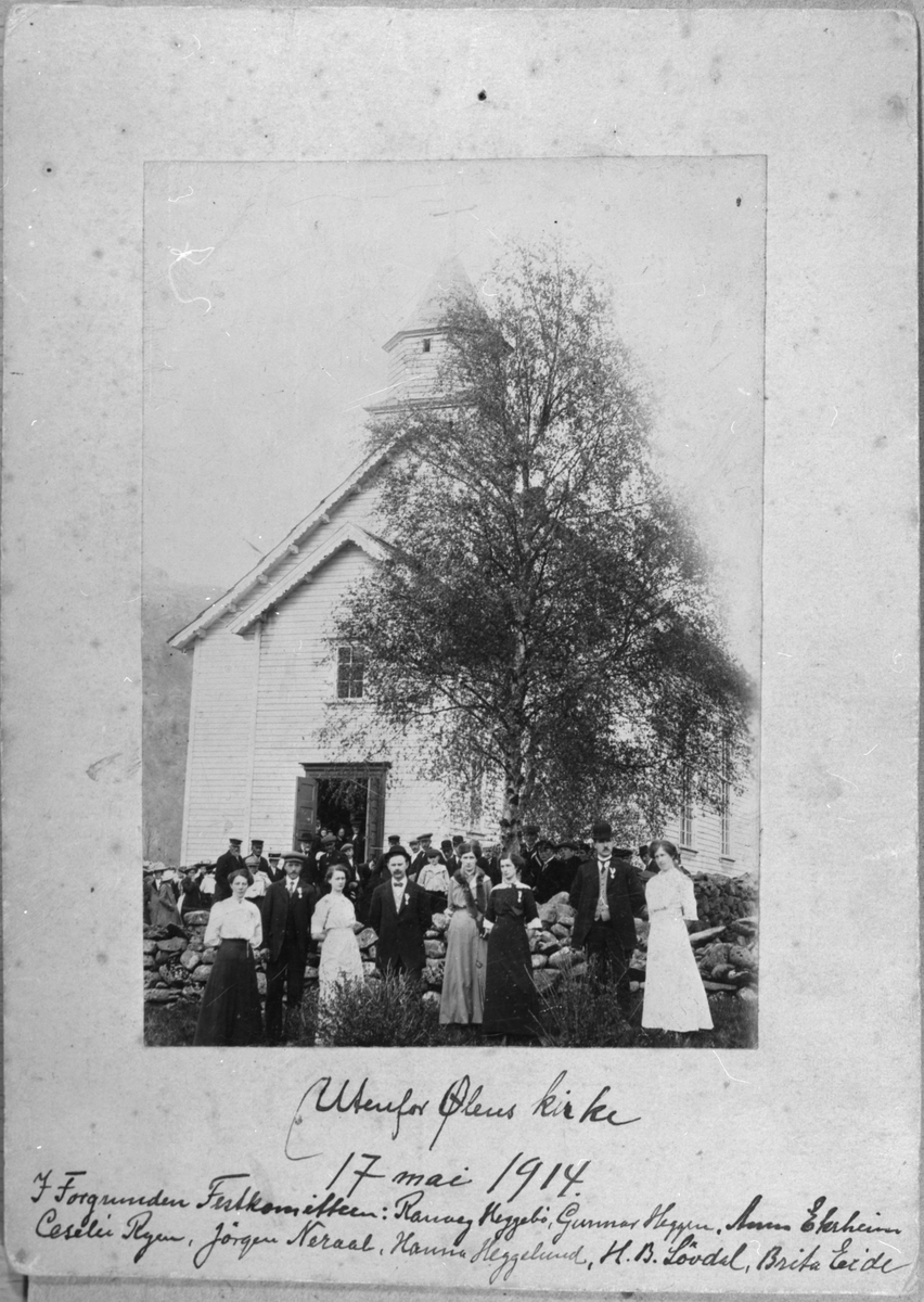 Ølen kyrkje under grunnlovsjubileet, 17. mai 1914. I forgrunnen er festkomiteen. Frå venstre: Ranveig Heggebø, Gunnar B. Heggen, Anna Ekrheim, Jørgen Nerål, Sesilie Ryen, Hanna Heggelund, Hans B. Løvdahl og Brita Eide.
