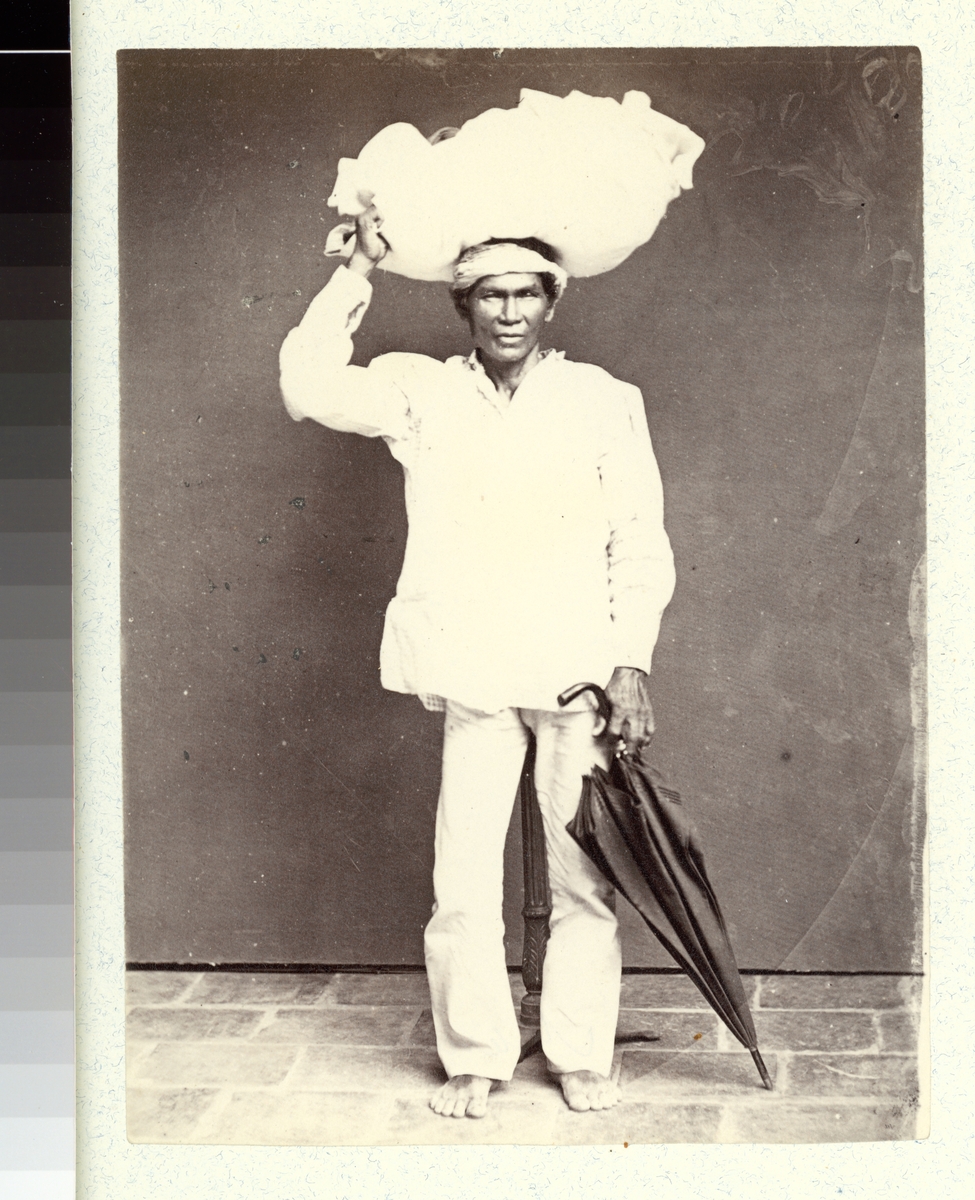 Bilden visar ursprungsbefolkningen Tagalog på Filipinernas största ö Luzon. Han bär en last på huvudet och håller en paraply i handen