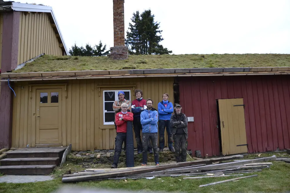 Bilde av arbeidsgjeng foran hus med torvtak