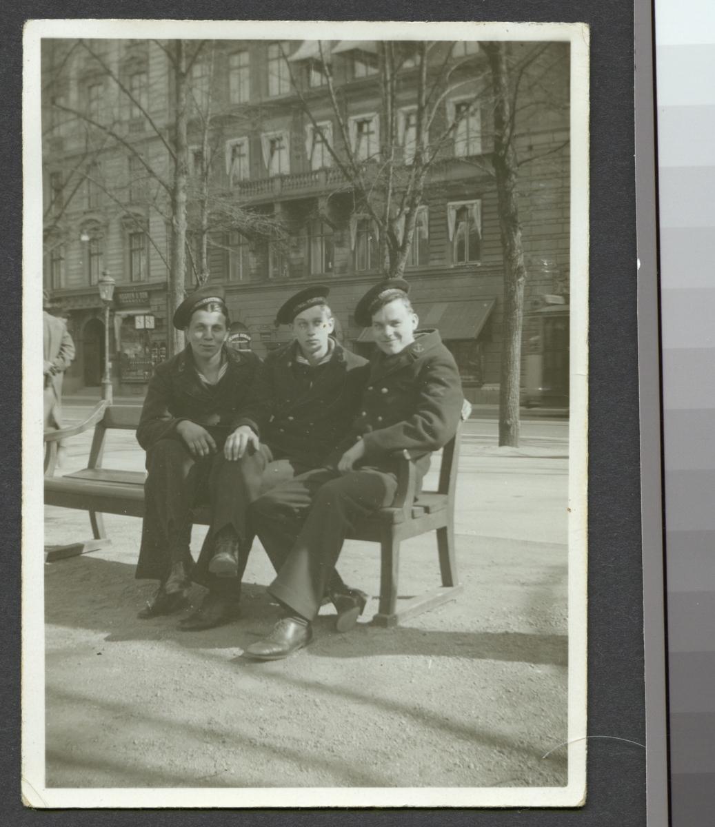 Bilden visar tre sjömän som sitter på en bänk i Kungsträdgården under en utflykt i staden.