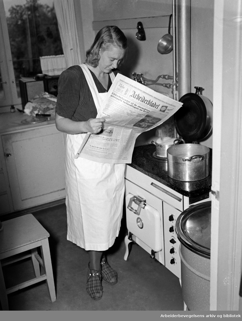 Kvinne leser Arbeiderbladet på kjøkkenet. Datert 30. september 1948.