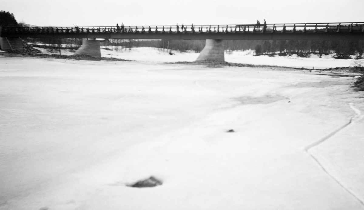 Ny bru over Glomma ved Hummelvoll (Håmålvoll) i Os i Nord-Østerdalen i 1956.  Fotografiet er antakelig tatt seint på vinteren, mens elveleiet ennå var dekt av is og snø, og mens vannstanden var lav.  Nybrua har både landkar og to støpte midtkar av betong.  Sjølve kjørebanen bæres av kraftige H-bjelker av stål.  Da fotografiet ble tatt var det en del mennesker oppå brua.  I bakgrunnen vokser det barskog.

Brua kostet 217 000 1956-kroner.