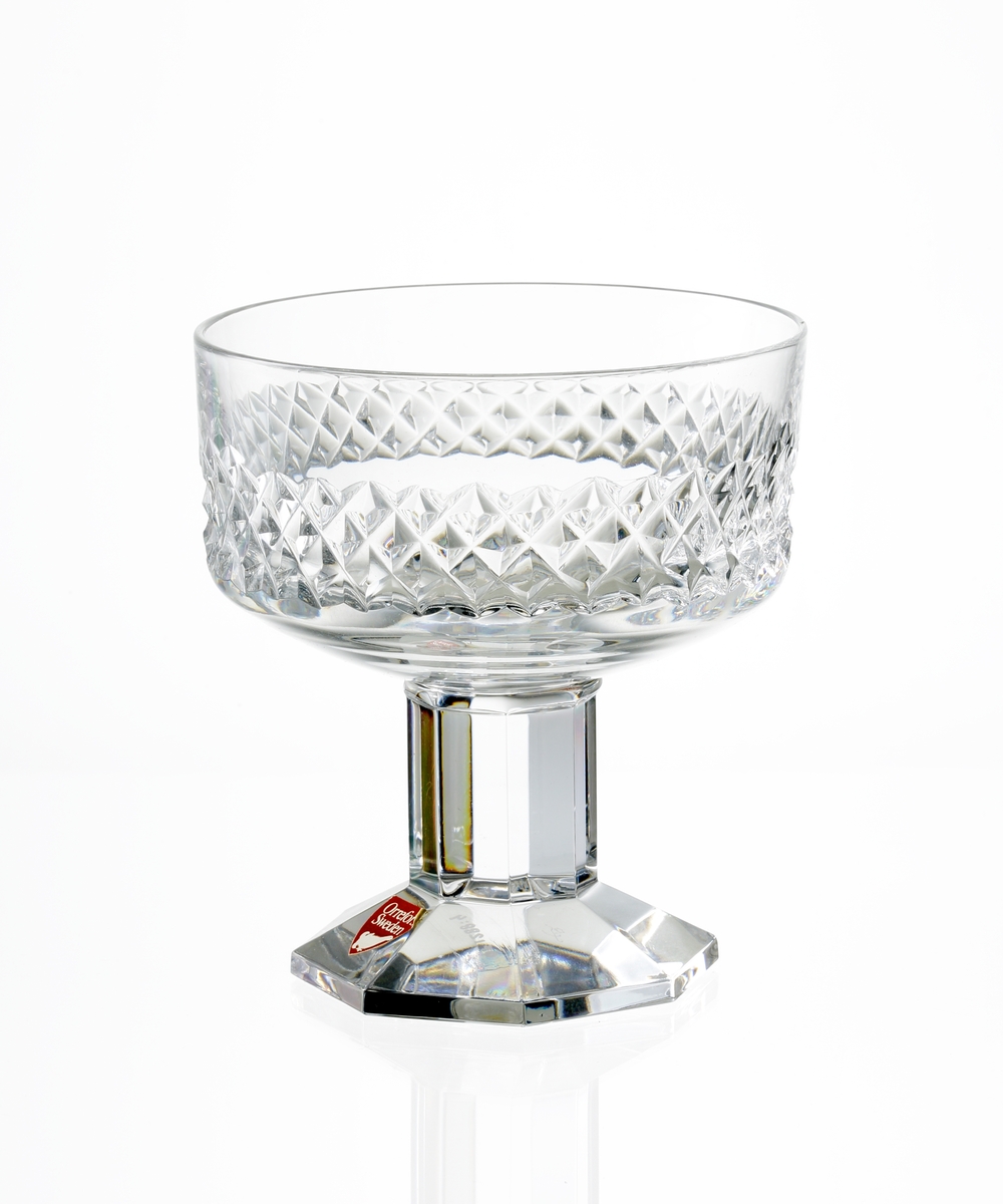 Design: Nils Landberg.
Champagneskål. Cylindrisk kupa med diamantslipad dekor på kupans nedre del. Fasettslipat lågt ben. 
Fasettslipad, åttkantig fot.