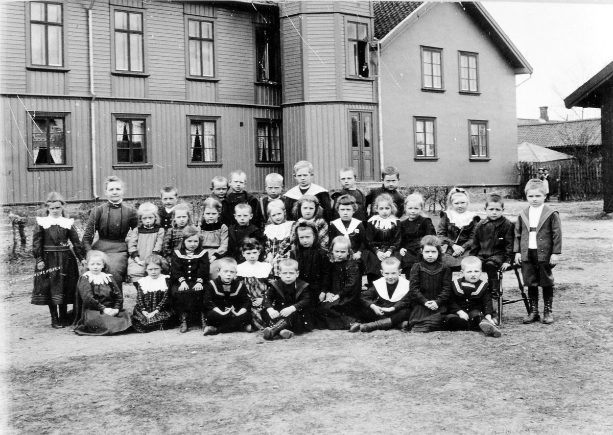 En skolklass med sin lärarinna utanför den gamla folkskolebyggnaden.
