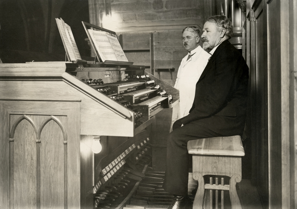 Musikdirektören och domkyrkoorganisten Ragnar Darell vid domkyrkans orgel 1929. Samma år hade den ombyggts under ledning av mannen i bakgrunden, orgelbyggaren Gunnar Setterquist d.ä. 
Ragnar Darell var domkyrkans organist från 1905 och tjänstgjorde parallellt som musiklärare vid Linköpings läroverk. Dessutom var han mångårig examinator av organister och kantorer i landet.
