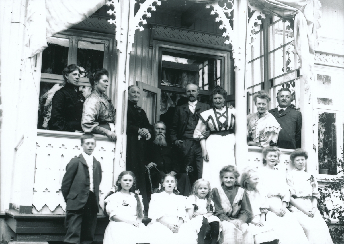 Gruppe selskapskledde mennesker på verandaen mot hagen av bestyrervillaen på Kistefos. Avbildet er familien Rydgren med forretningsforbindelser og venner.