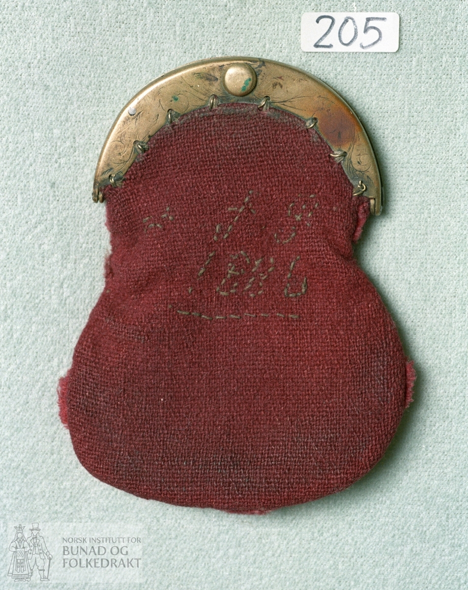 Pung av burgunderrødt ullerret. Pungen har to rom. Initialer og årstall på framsida, trolig 1886. Messinglås med gravert rankebord. Bredde lås:  9 cm.