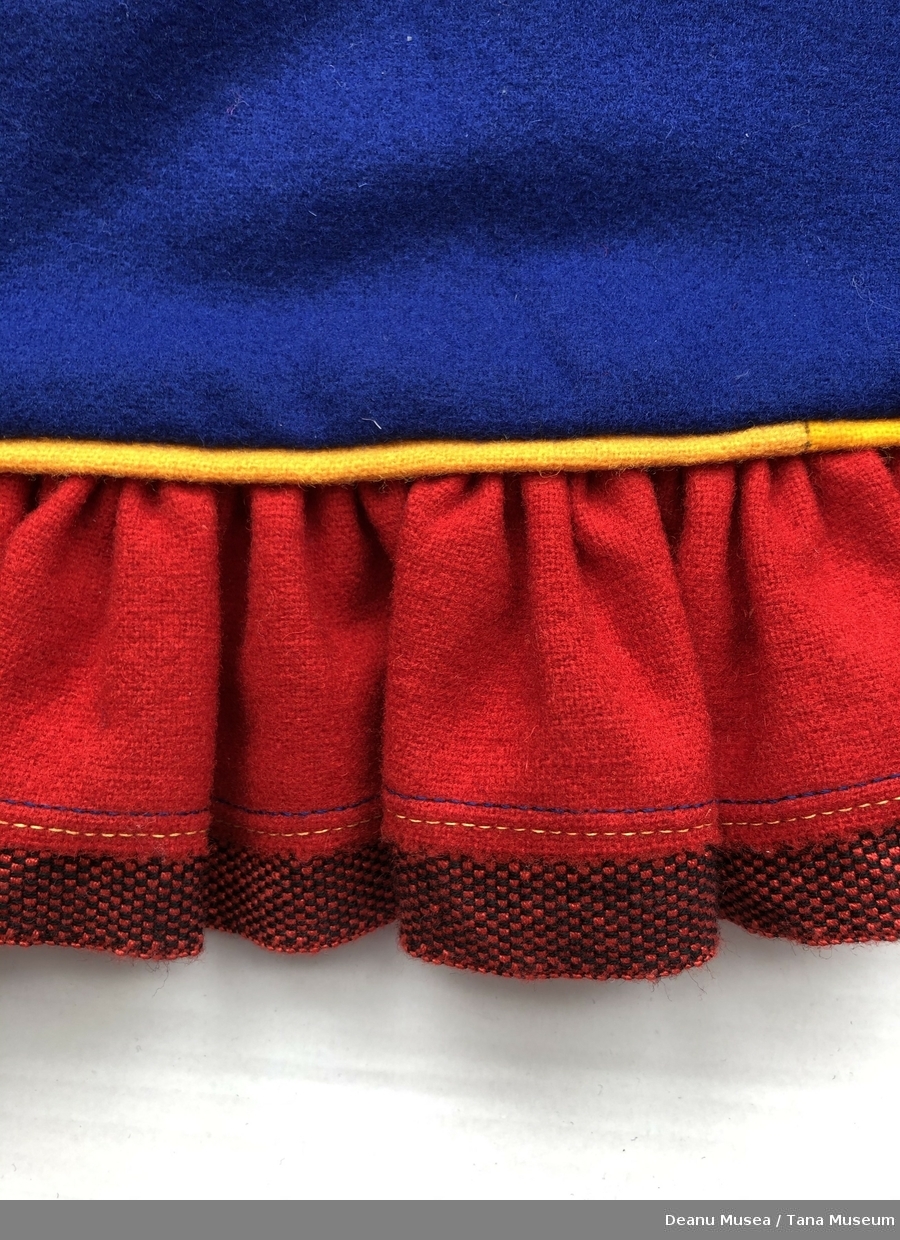 Blå jentekofte i ullklede fra Alleknjarg med røde pyntekanter. Rød holbi med gul pyntekant og rød/sort vevet bånd.