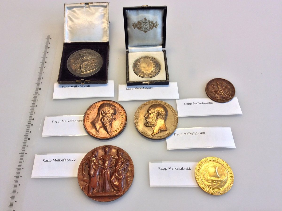 Etui med gråfarget mynt avbildet med en karakter fra gresk eller romersk mytologi på den ene siden og en laurbærkrans på den andre