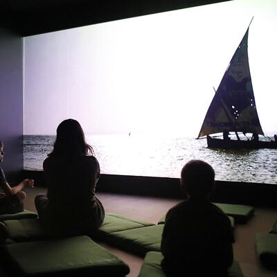 Barn ser på en film om utvandring som er en del av utstillingen