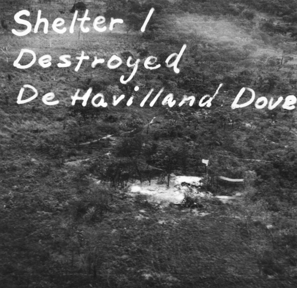 Flygspaningsbild av katangesiskt flygplan De Havilland Dove i flygplanvärn. Foto taget efter anfall av F 22 under Kongokrisen, den 29 december 1962. Med påritad spaningsinformation "Shelter 1 Destroyed De Havilland Dove".