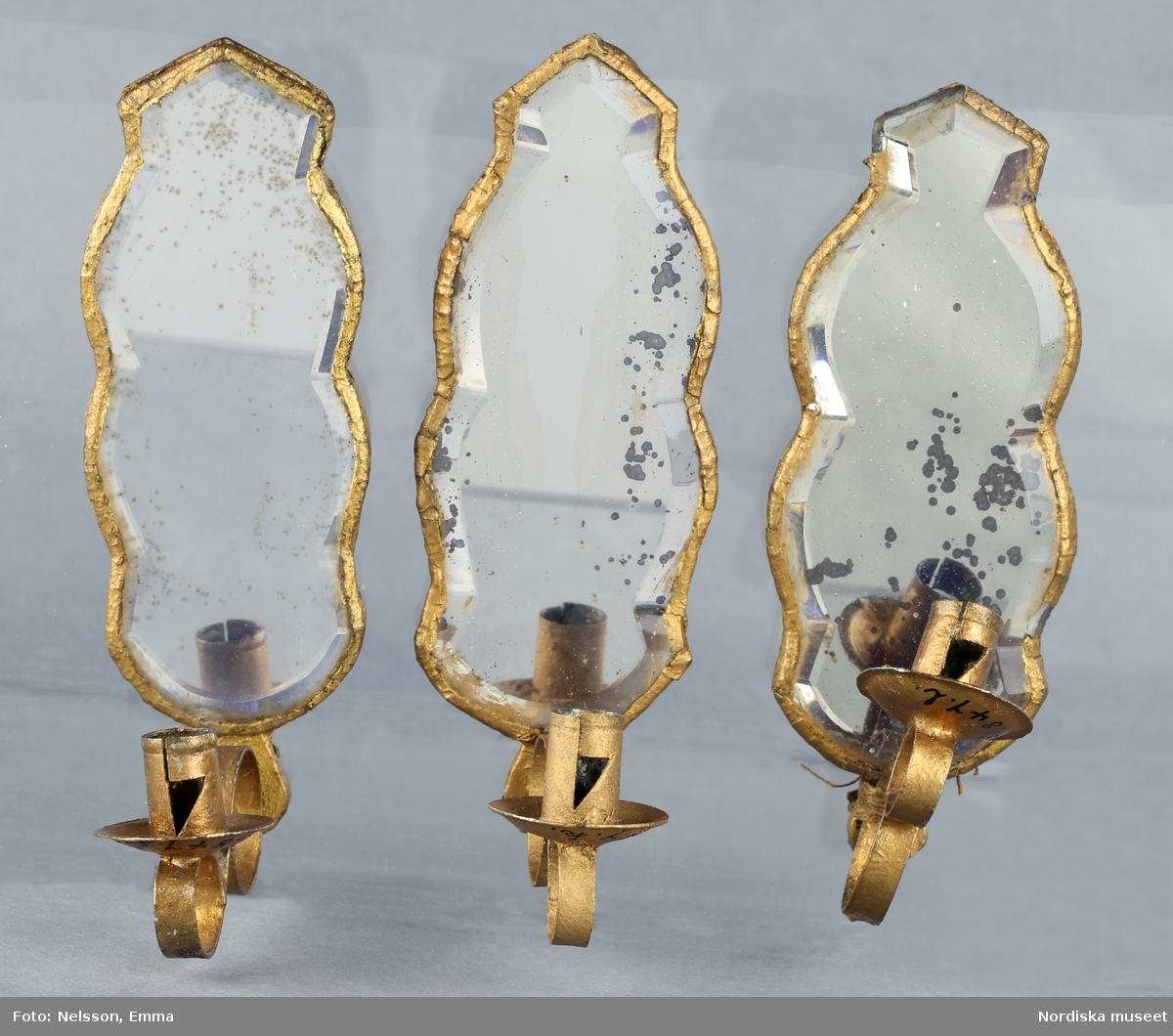 Inventering Sesam 1996-1999:
H 10,5 cm
12 st spegellampetter, konturerat spegelglas med facettslipning, bakstycke av furu. Ljusarm av ihoprullat stålband. Några glas med fläckar.
Tillhör dockskåp 151.825.
Birgitta Martinius 1996