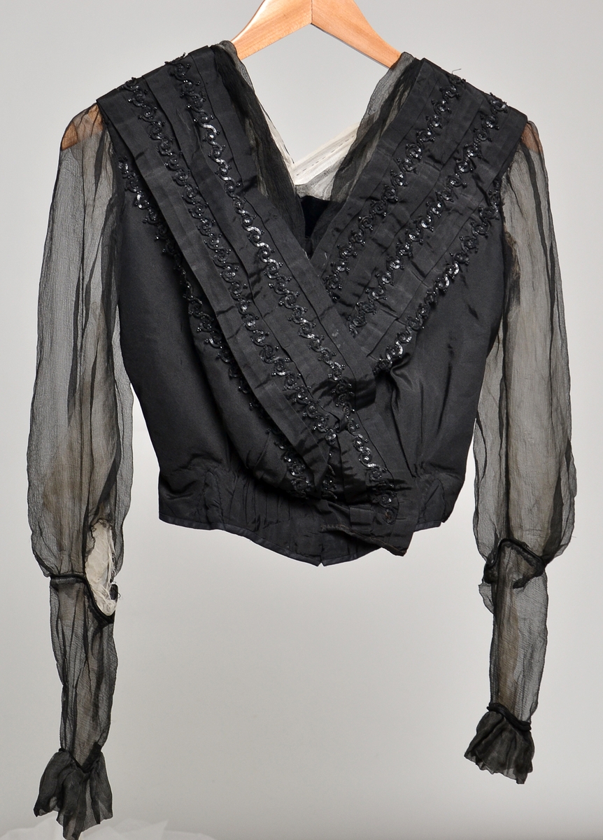Sort bluse dekorert med sorte perler og paljetter på bolen og ermer og "krage" av sort og hvitt chiffong
