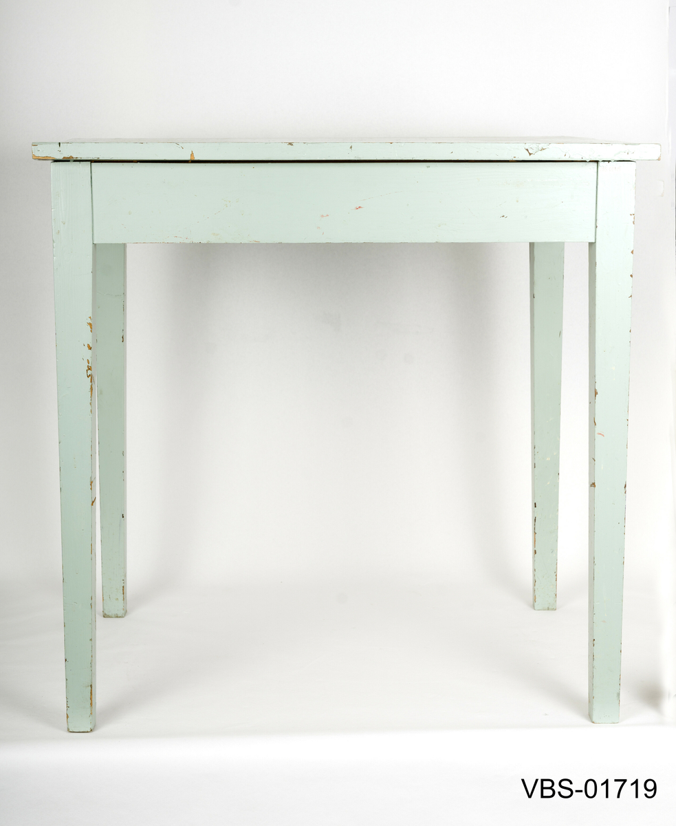 Enkelt bord med rette ben litt  avsmalnende nede. Håndverk arbeidsbord.
Bordplaten er laget av tre limte brett og med innvendige forsterkninger i hjørnene.