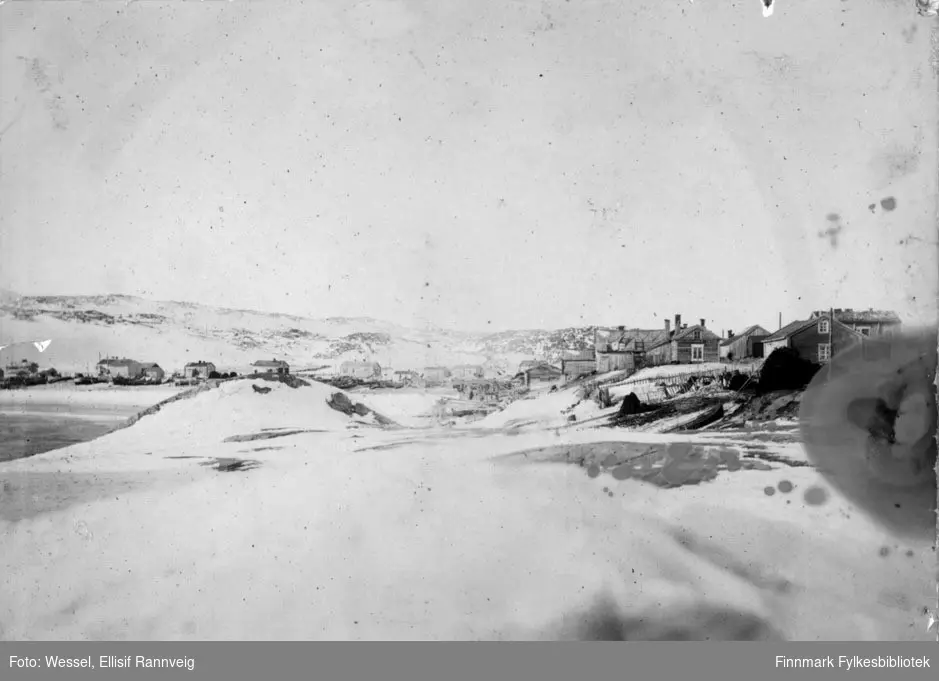 Bugøynes i 1898. Bildet er tatt ved fjæra og oppover mot bebyggelsen. Bildet er svært bleket midt på bildet, men detaljene er gode på sidene av bildet.