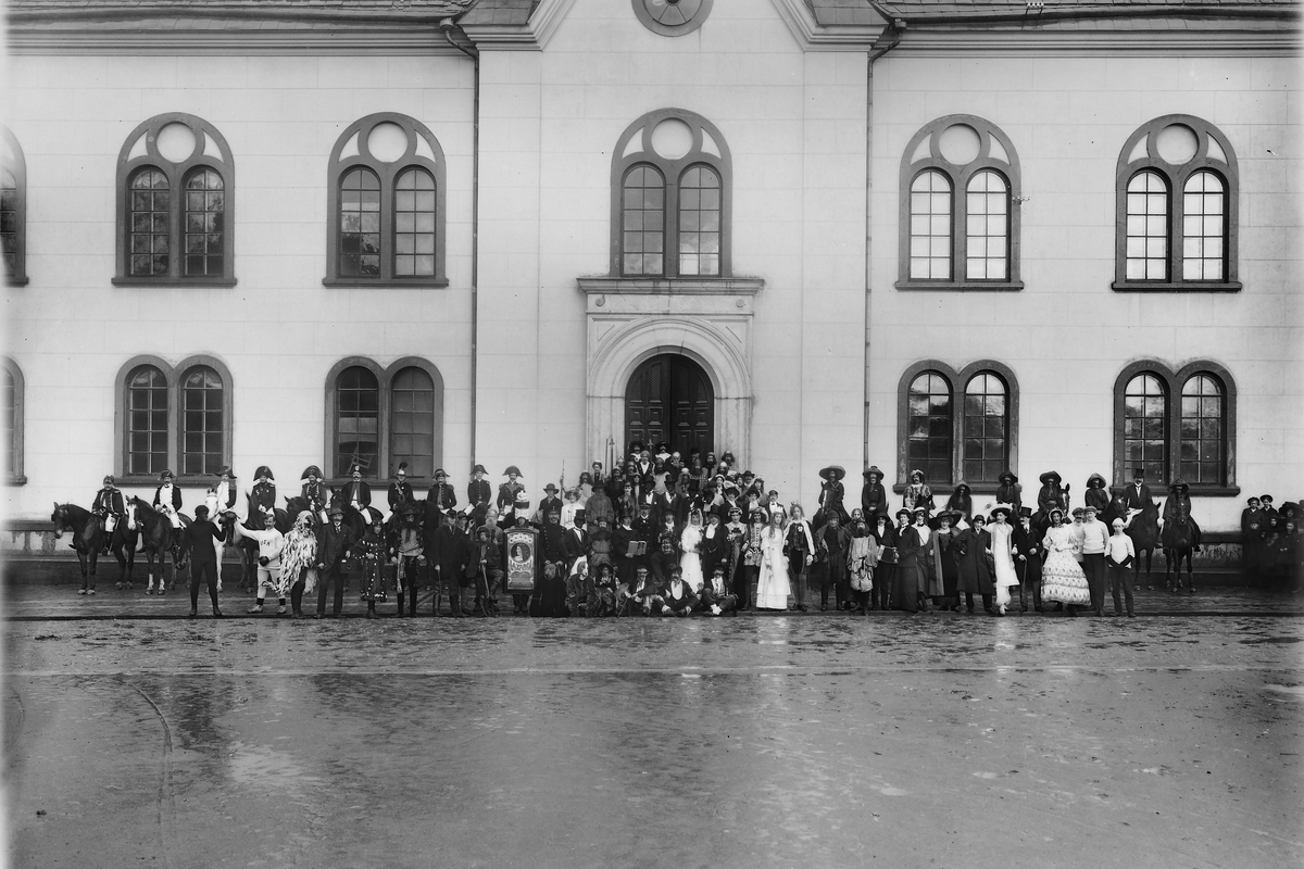 Majgubbar? 
Vid läroverkets västra gavel, Linköping. Linköpings stadshus. Storgatan i Linköping. 
Byggnaden byggdes om 1921 till stadshus och då togs denna entré bort. Skola. Spex. Studenter. Utklädnad. Majgubbar.