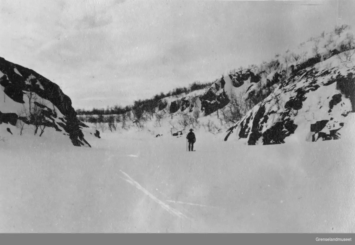 Adamselv, strykpartiet ca. 3 km ovenfor Vallejohka, en mann på ski står ute på isen, ca 1919.