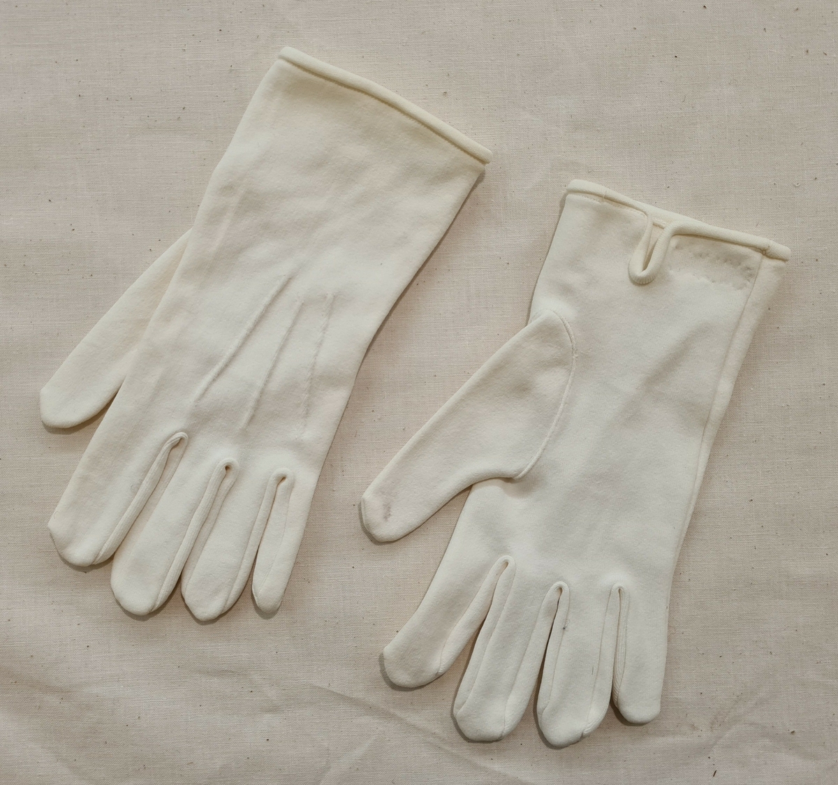 Ett par handskar av nylon till polisuniform. Handskarna har tre sydda veck på ovansidan. På vänster handske finns en påsydd etikett med en mycket sliten text. Trol. står där: ''100% Nylon S-T-R-E-T-C-H Size 13/15 Made in Hong Kong''.

21 275:a Höger handske.
    ''       :b Vänster handske.