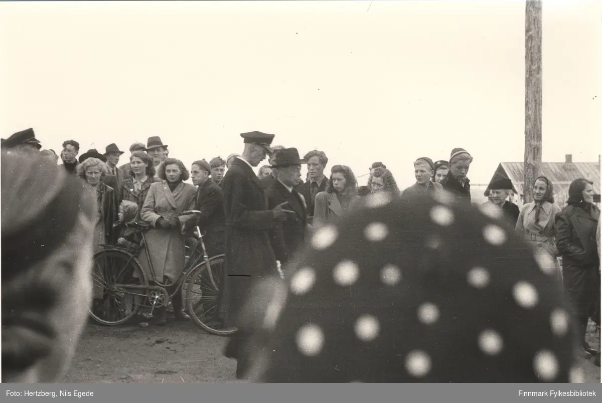 Kong Haakon VII på besøk i Vadsø i 1946. Til høyre siden går fylkesmann Hans Julius Gabrielsen. Mange mennesker har kommet til stede for å se på kongen. Se også bildene 264-267.