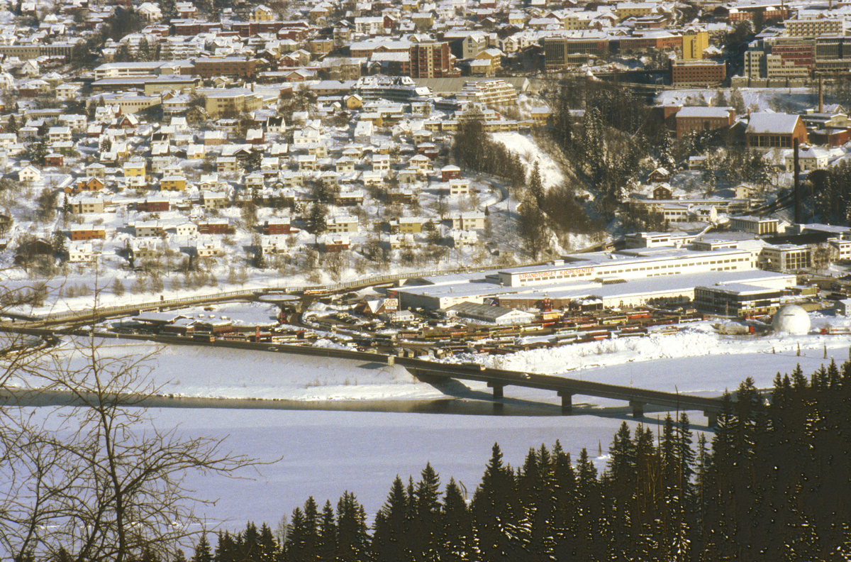 Lillehammer. Nedre bydel, Strandtorget, Lillehammer bru og Gudbrandsdalslågen. Strandtorget ble brukt som bussterminal under OL 1994. Utsikt mot øst fra Saksumsdalsvegen.