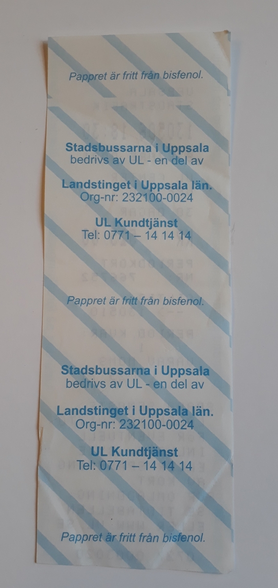 UL periodkort 30 dagar, utskrift på kvittopapper.
Periodbiljetten, eller kortet, är utskrivet med svart på en vit pappersremsa med diagonala blå ränder. Tryckt i blått längs med kanten, står det upprepande: "Utfärdad på försäljningsställe".
Text: "Uppsala stadstrafik
130506 18:30
Säljare 0001
UL Center
Uppsala
30 dagar
Kr 525.00
Periodkort
Nr: 766752
Giltig - 130510
Period kvar:
1
Varav moms
29.71"
Längst ner står text om villkor för biljetten.
På baksidan står kontaktuppgifter till UL mm, samt texten "Pappret är fritt från bisfenol".