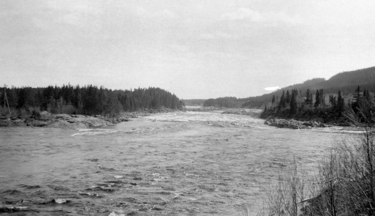 Glomma fotografert i medstrøms retning mot Braskereidfossen i Våler kommune i Hedmark i 1919. Bildet ser ut til å være tatt i medstrøms retning, og vi aner en tømmerhaug nederst i fossestrykene.