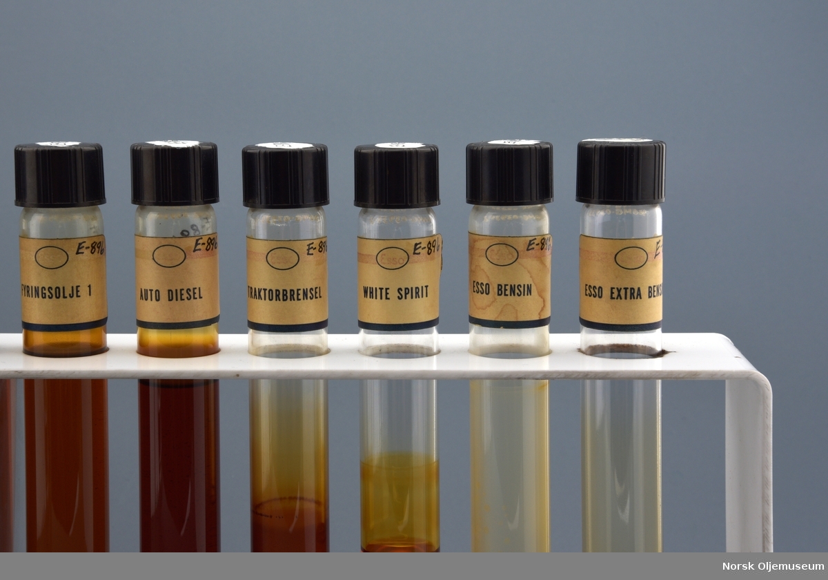 Stativ med tolv oljeprøver i reagensrør. 

Oljeprøvene er eksempler på forskjellige oljekvaliteter fra lett- til tungolje produsert ved Vallø Oljeraffineri.