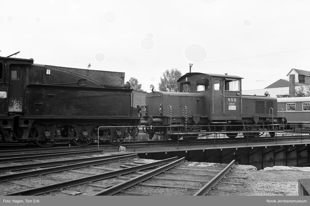 Damplokomotiv 21e 207 utenfor lokomotivstallen på Hamar. På svingskiven skiftetraktor Skd 220 129