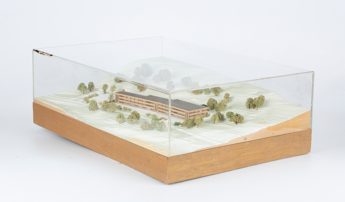 Modell av planlagt næringsbygg i terreng (Oksval, Nesodden). I kasse av klar plast.