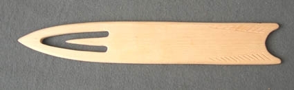 Bandkniv, eller bandsticka, av björk. Den ena kortänden är spetsig och har ett täljt urtag som bildar en inre spets. Bakänden är konkav och har ett enkelt skuret mönster på fram- och baksidan. Prismärkt 25:75 kronor i "Förslag till Modell-Arkiv".